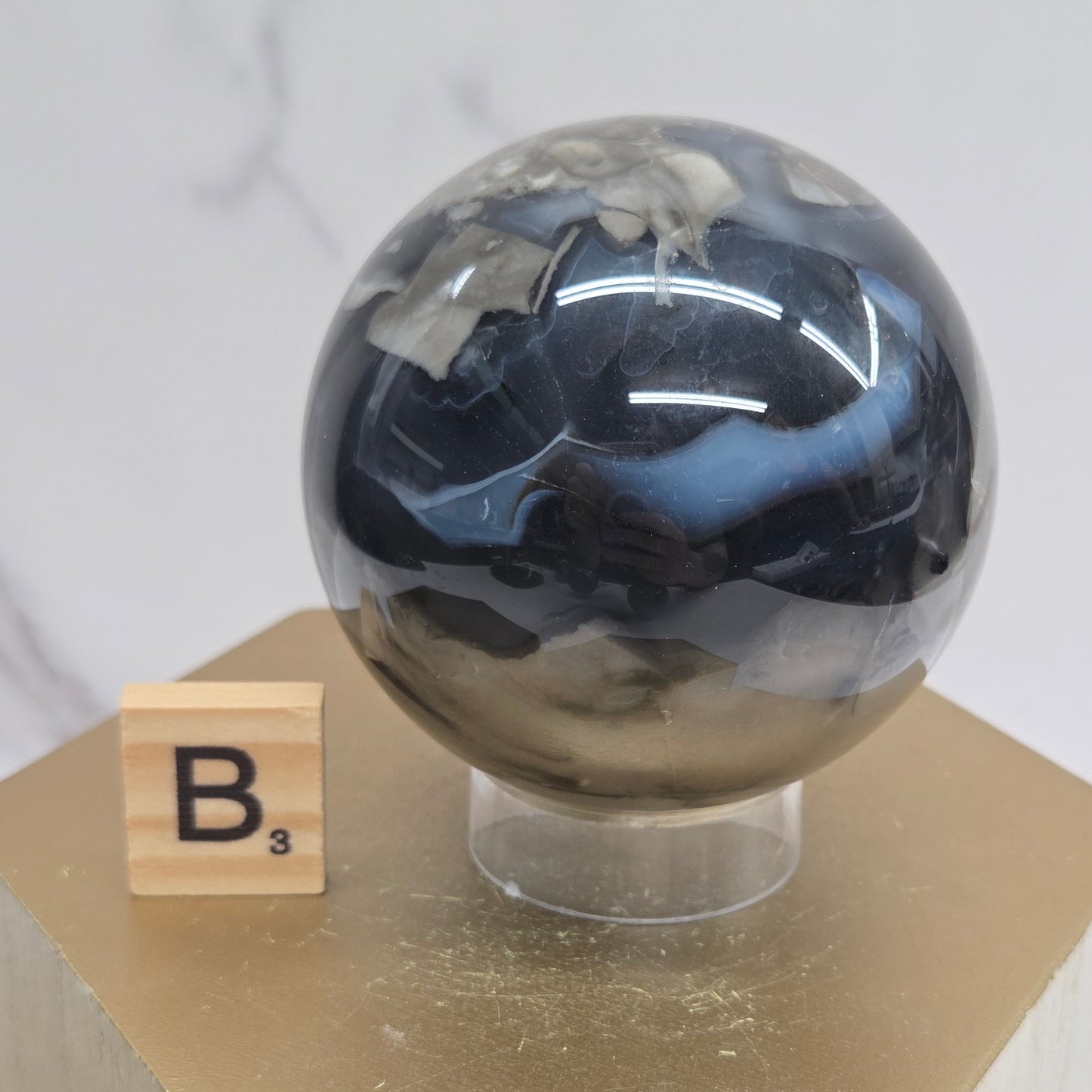 Brown and black crystal spheres on acrylic holders and a wooden stand against a neutral background