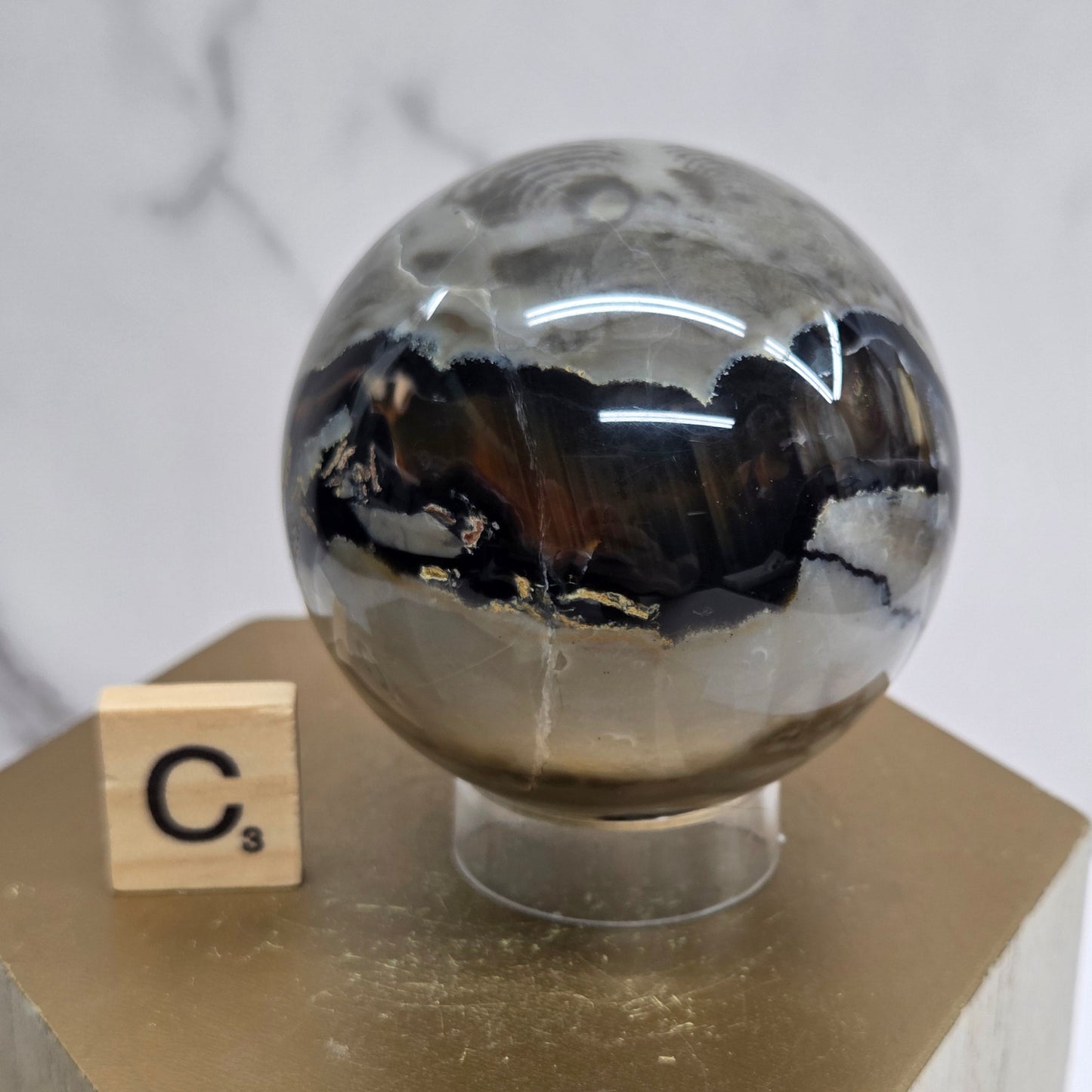 Brown and black crystal spheres on acrylic holders and a wooden stand against a neutral background