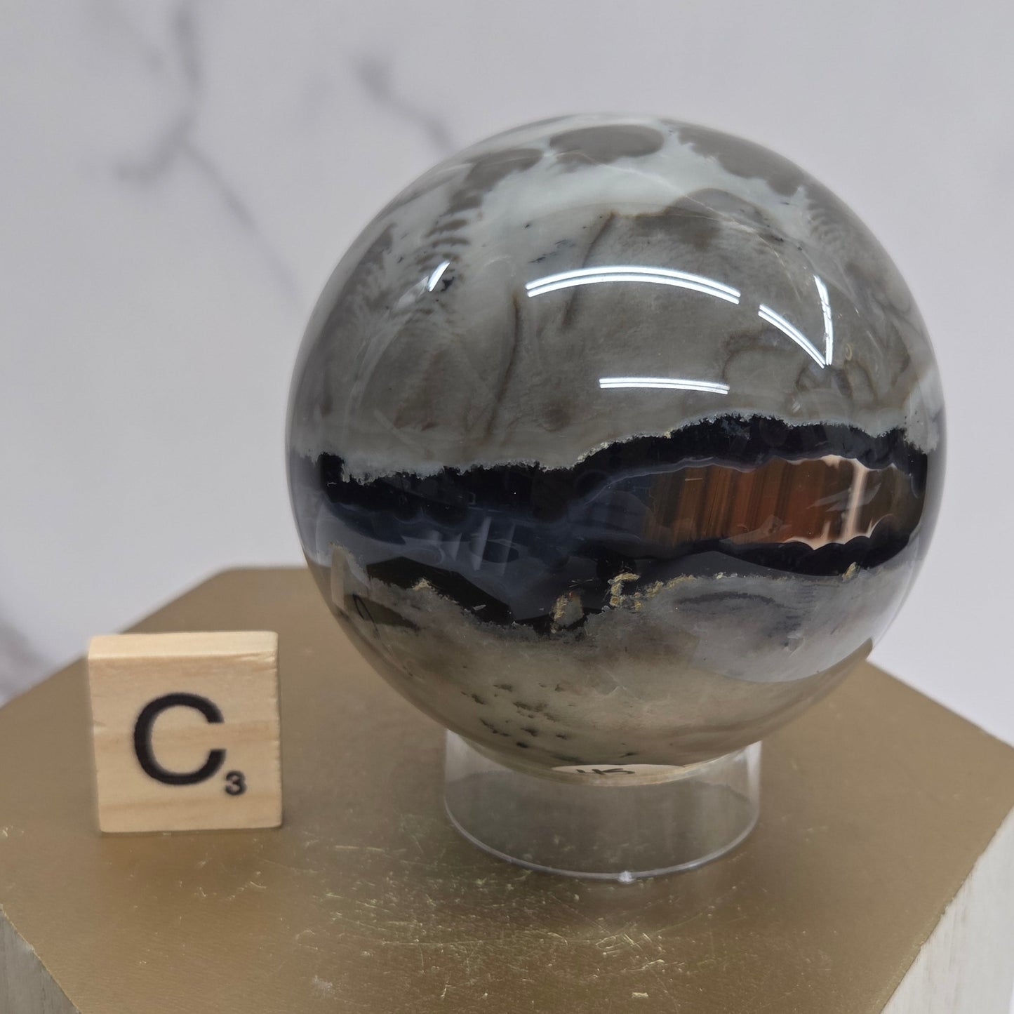 Brown and black crystal spheres on acrylic holders and a wooden stand against a neutral background