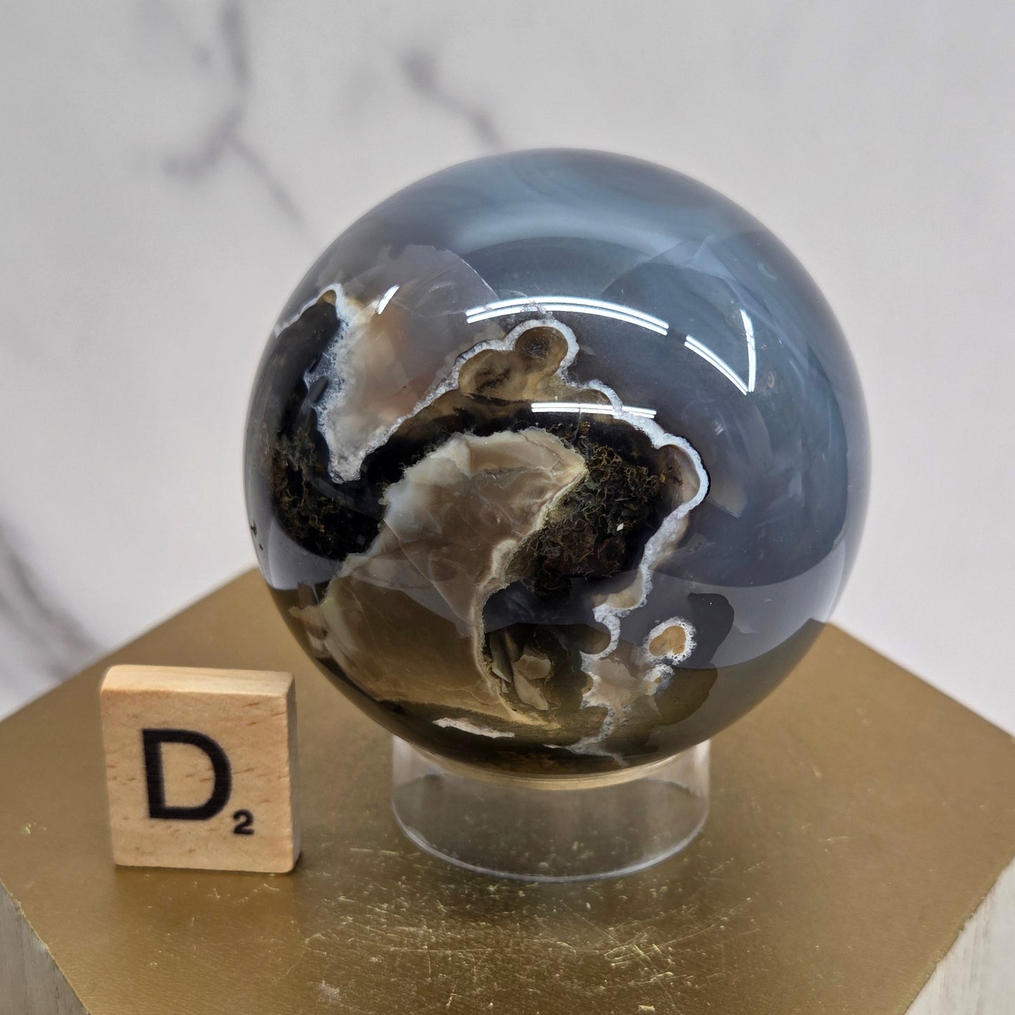 Brown and black crystal spheres on acrylic holders and a wooden stand against a neutral background