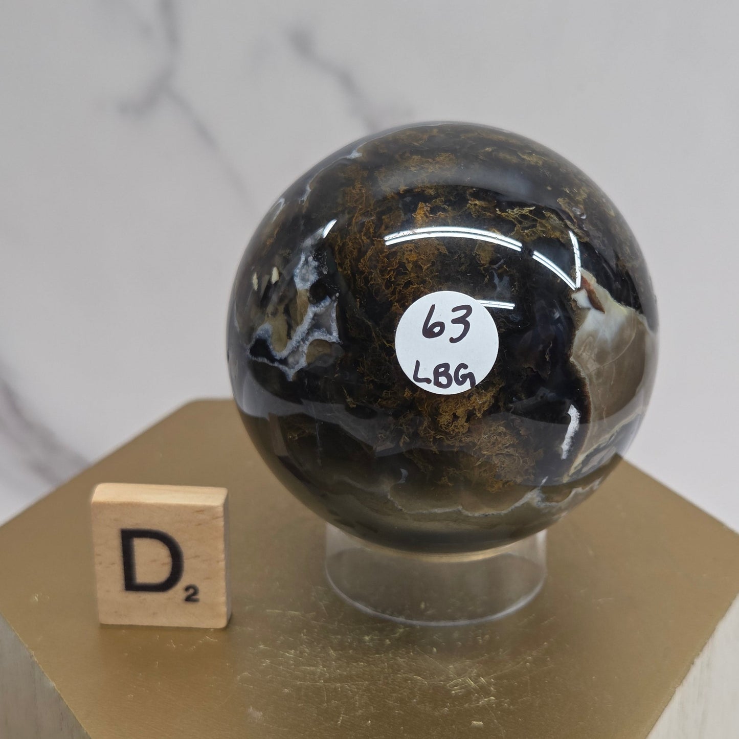 Brown and black crystal spheres on acrylic holders and a wooden stand against a neutral background