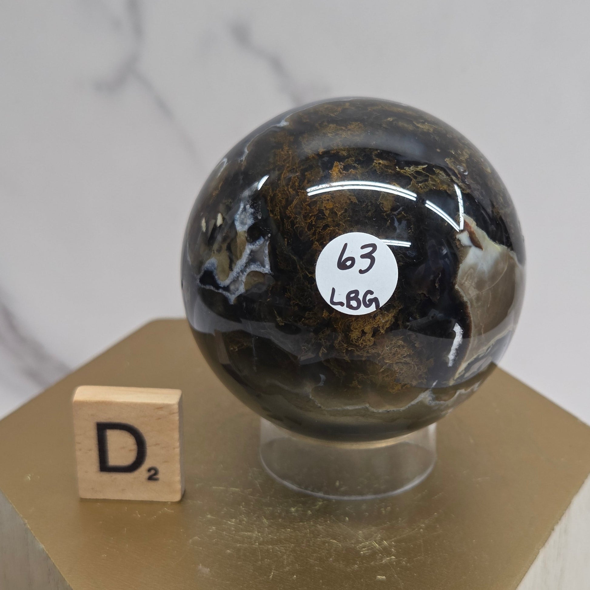 Brown and black crystal spheres on acrylic holders and a wooden stand against a neutral background