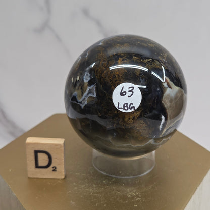 Brown and black crystal spheres on acrylic holders and a wooden stand against a neutral background