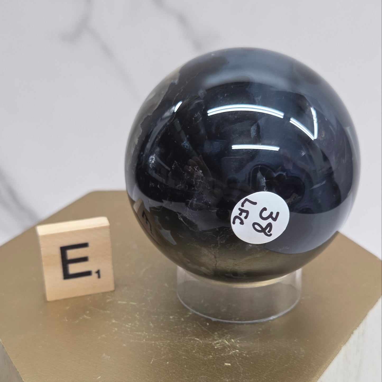 Brown and black crystal spheres on acrylic holders and a wooden stand against a neutral background