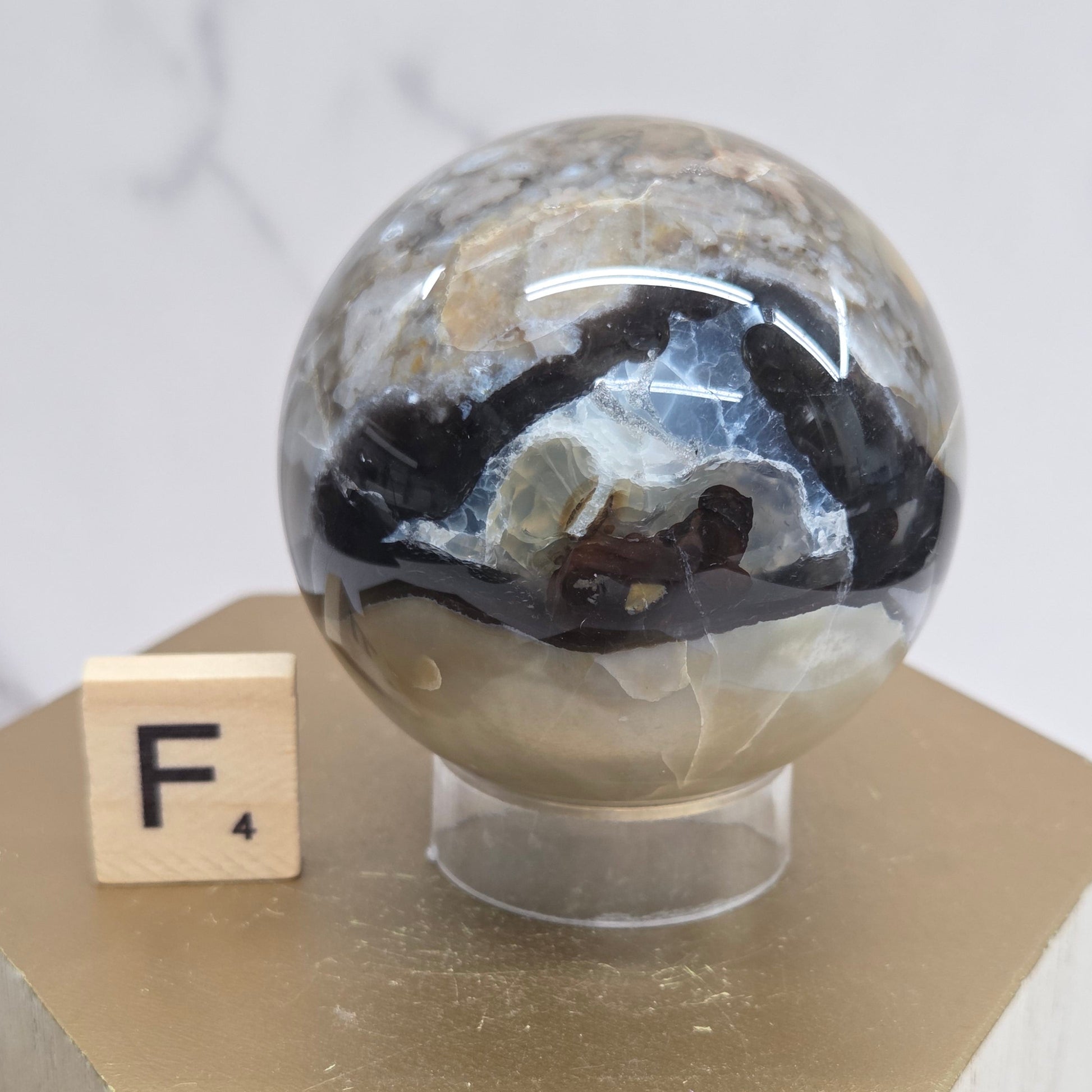 Brown and black crystal spheres on acrylic holders and a wooden stand against a neutral background
