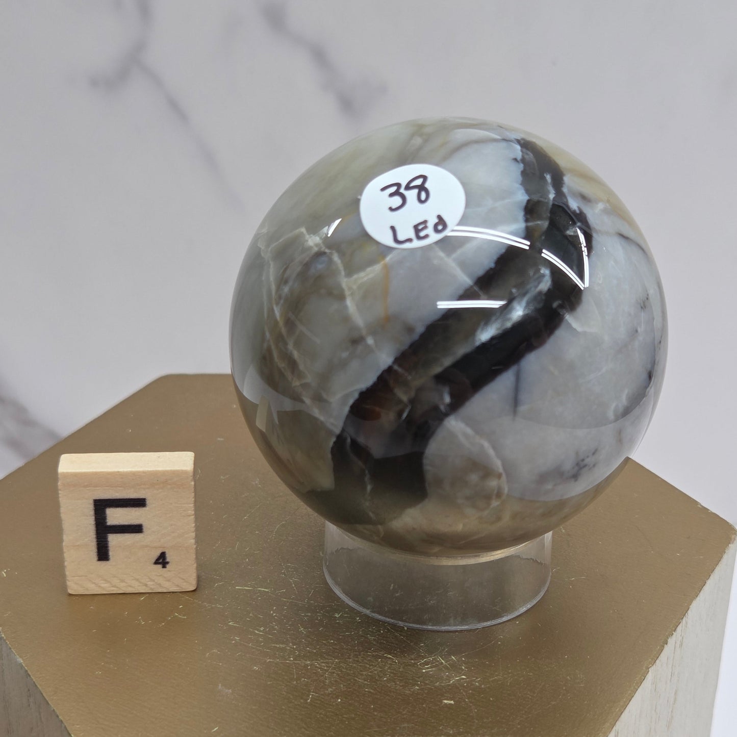 Brown and black crystal spheres on acrylic holders and a wooden stand against a neutral background