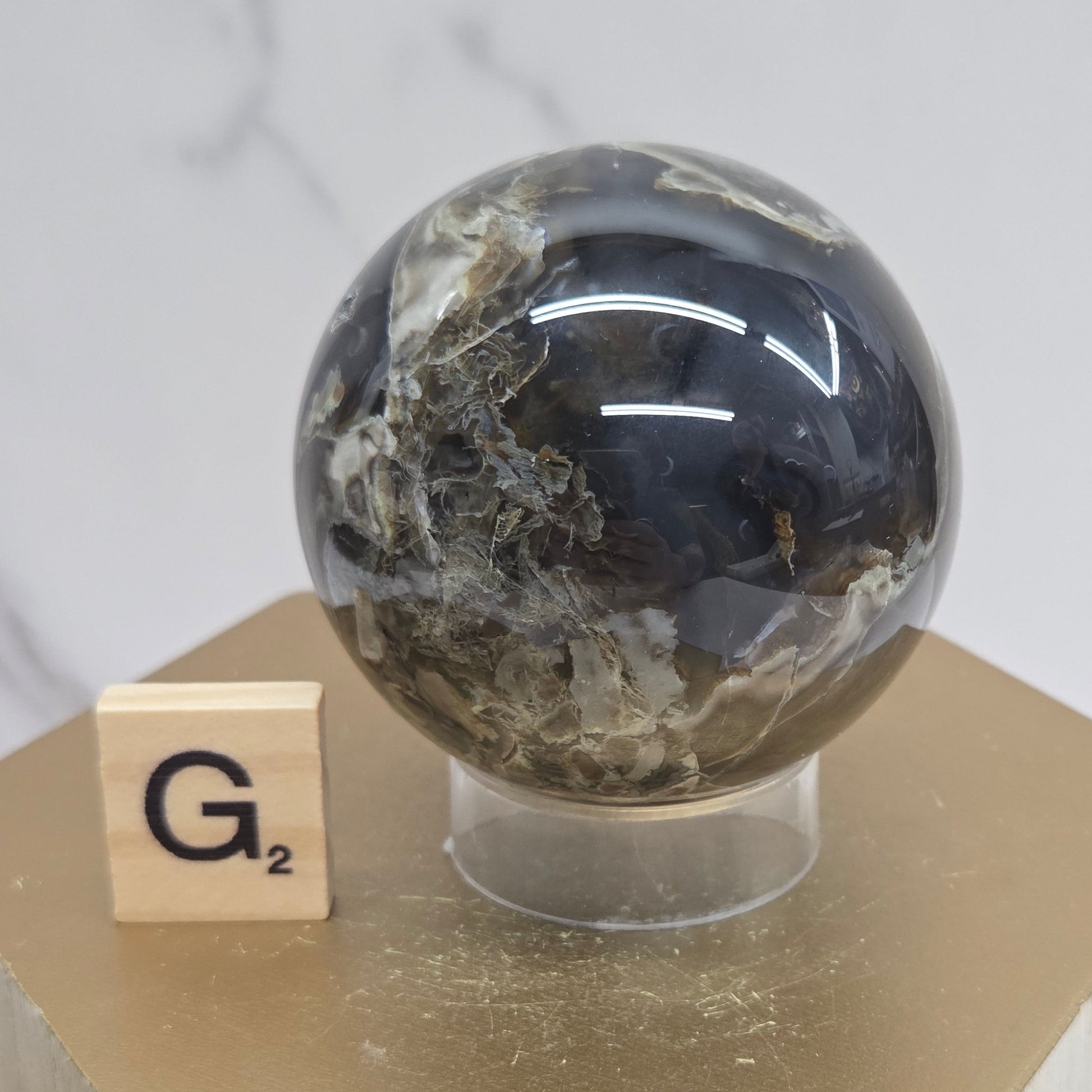 Brown and black crystal spheres on acrylic holders and a wooden stand against a neutral background