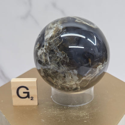 Brown and black crystal spheres on acrylic holders and a wooden stand against a neutral background
