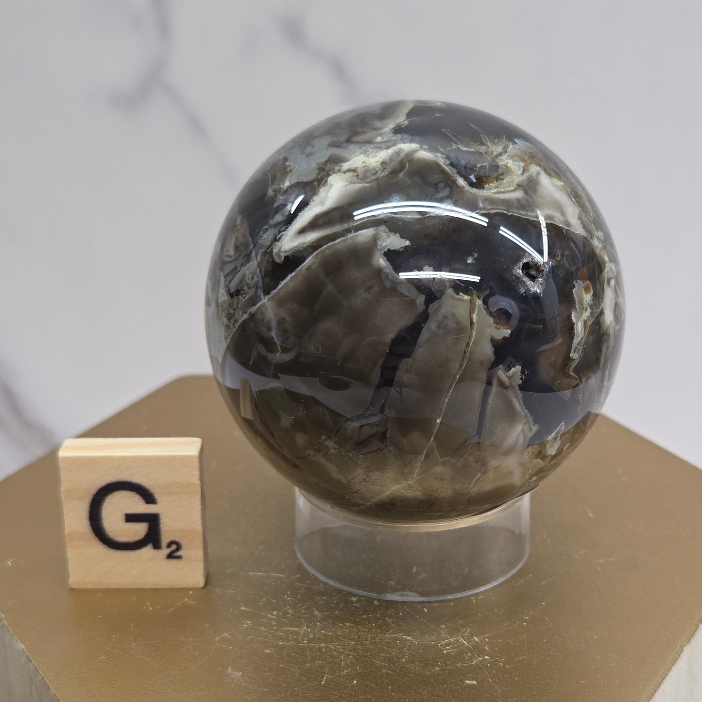 Brown and black crystal spheres on acrylic holders and a wooden stand against a neutral background
