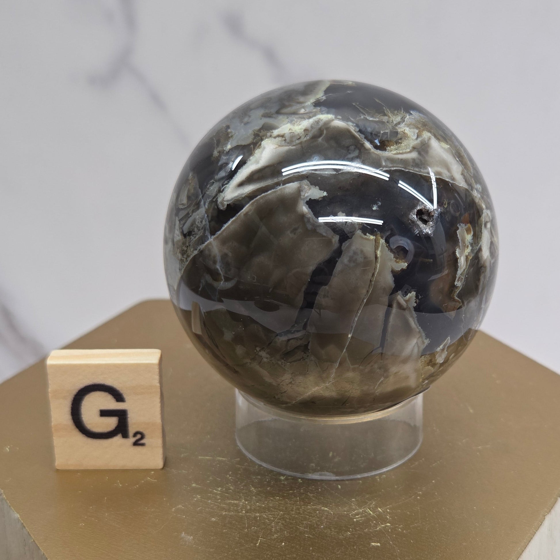 Brown and black crystal spheres on acrylic holders and a wooden stand against a neutral background