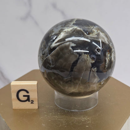 Brown and black crystal spheres on acrylic holders and a wooden stand against a neutral background