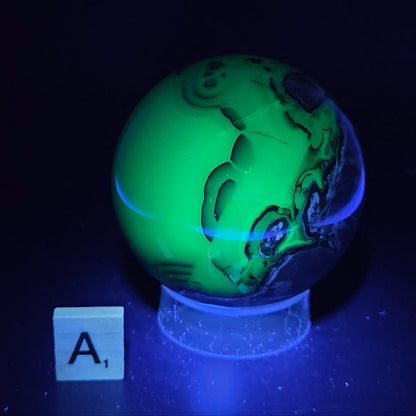 Brown and black crystal spheres on acrylic holder under UV light against a neutral background