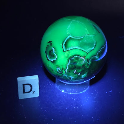 Brown and black crystal spheres on acrylic holder under UV light against a neutral background
