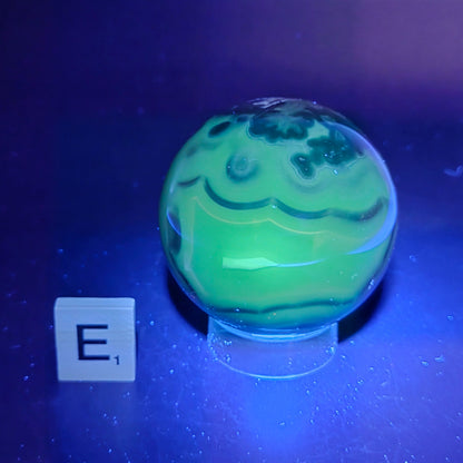 Brown and black crystal spheres on acrylic holder under UV light against a neutral background