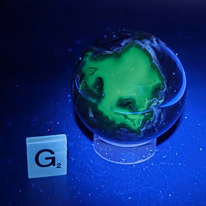 Brown and black crystal spheres on acrylic holder under UV light against a neutral background
