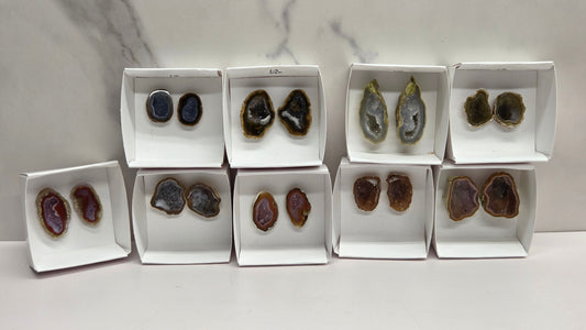 Set of geode crystals in small white boxes on a marble background