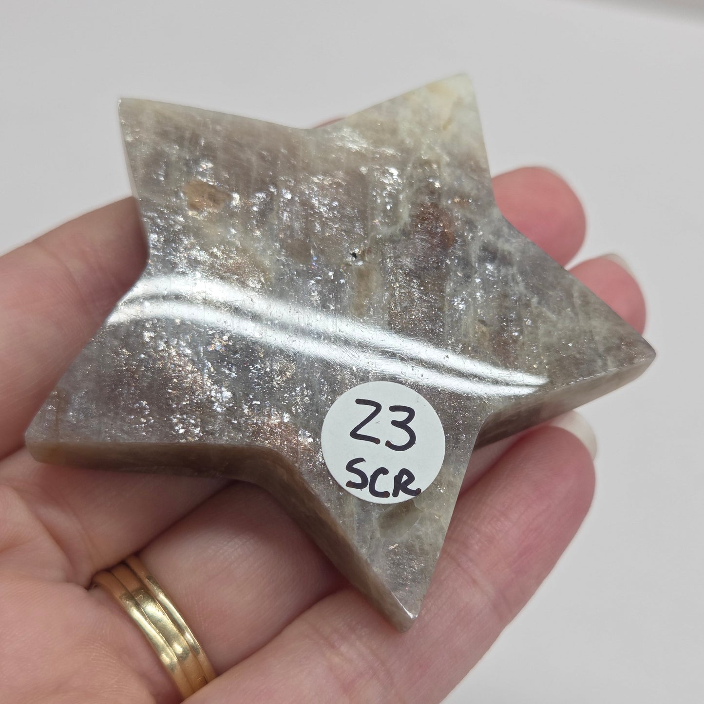Star-shaped crystal held in a hand with a visible label on a white background