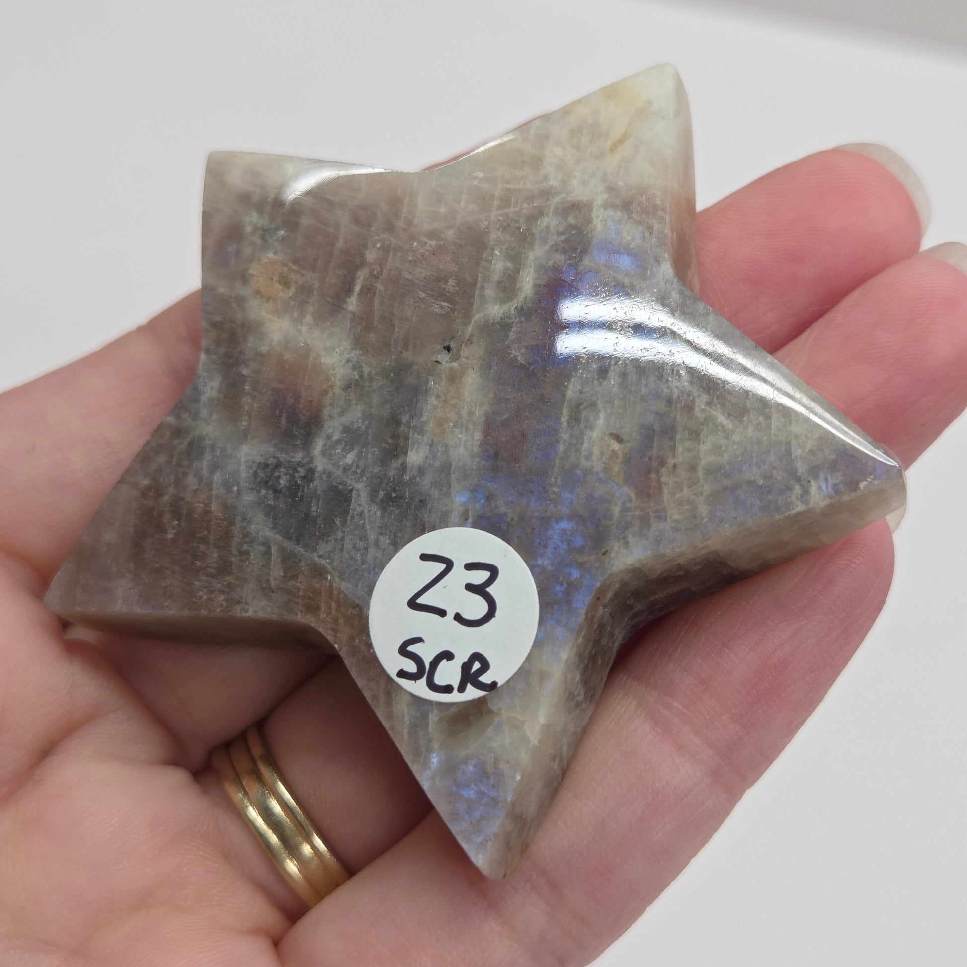 Star-shaped stone held in a hand with a label on a white background