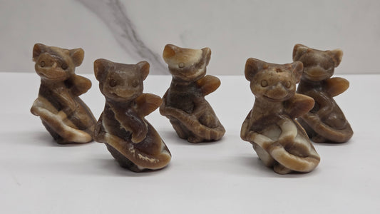 Five small brown dragon figurines on a white surface with a marble-patterned wall in the background.