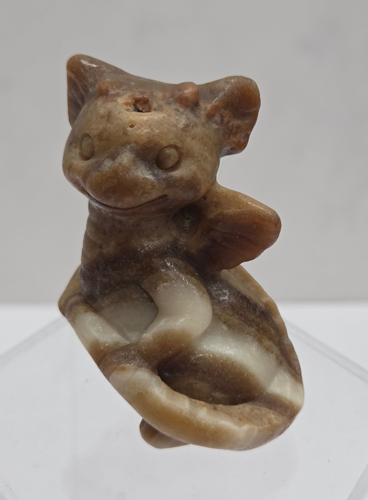 Brown calcite sculpture of a dragon on a white background