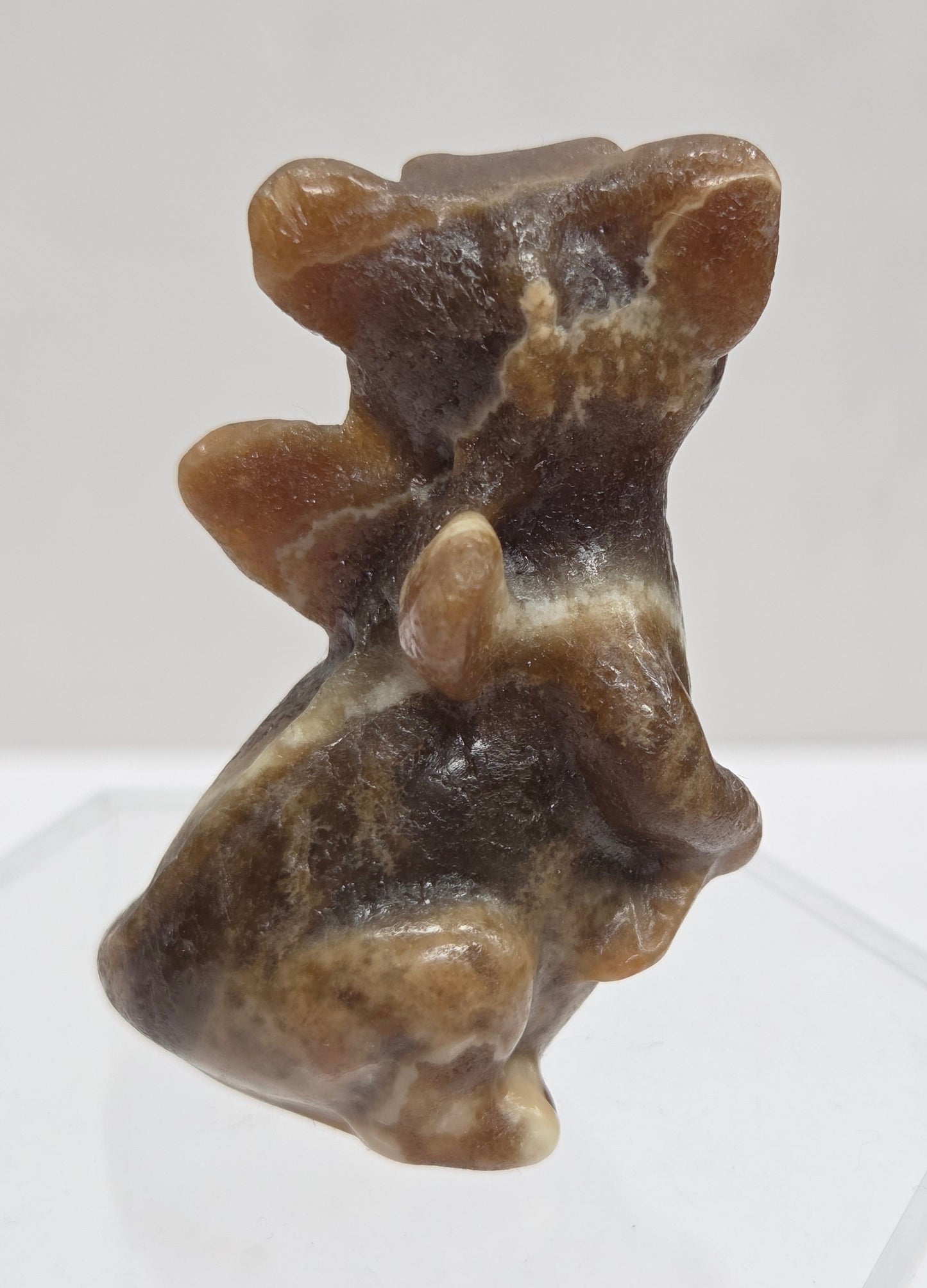 Brown calcite sculpture of a dragon on a white background