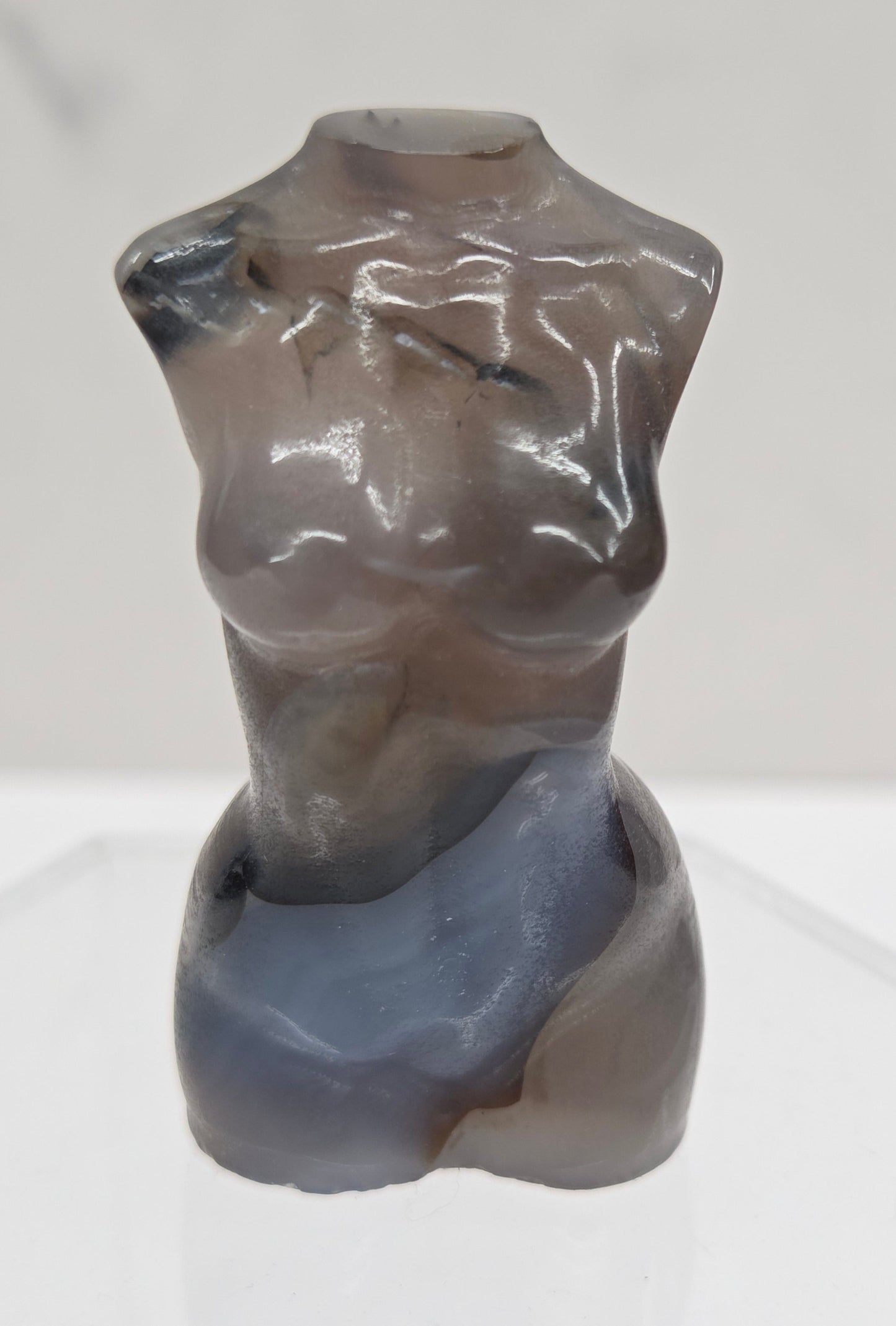 Gray stone sculpture of a woman's torso on a white background