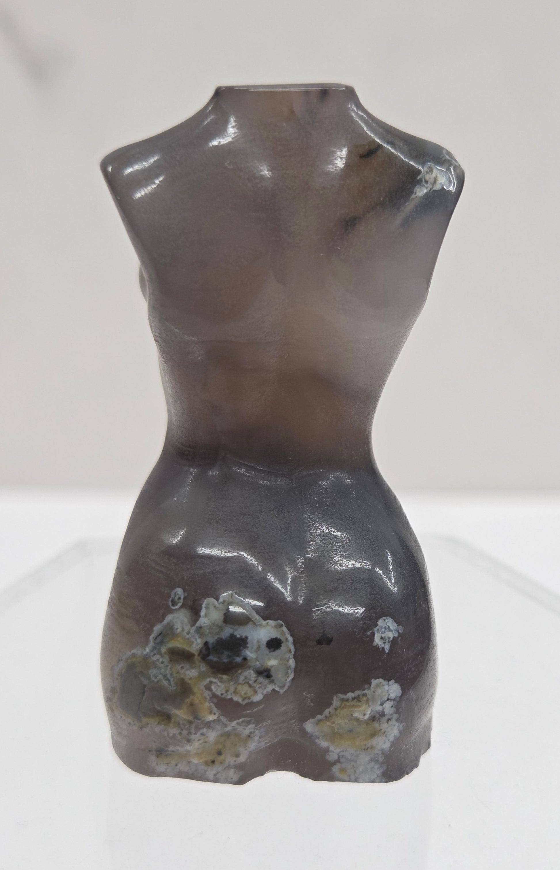 Gray stone sculpture of a woman's torso on a white background