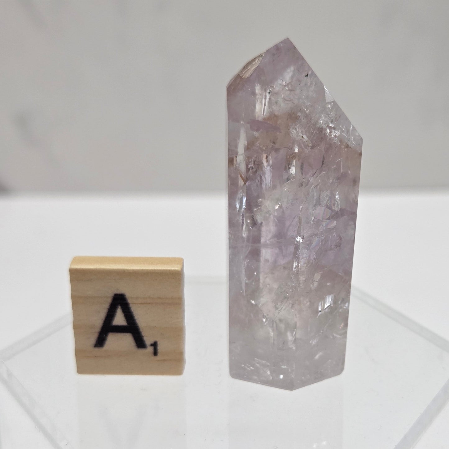 Crystal-like object on a white surface with a wooden block featuring the letter 'A'.