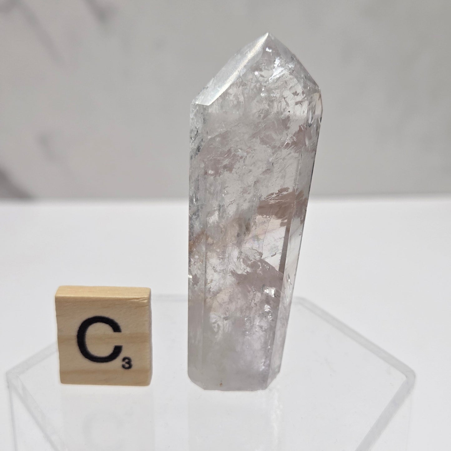 Clear crystal on a white surface with a wooden block featuring a symbol.