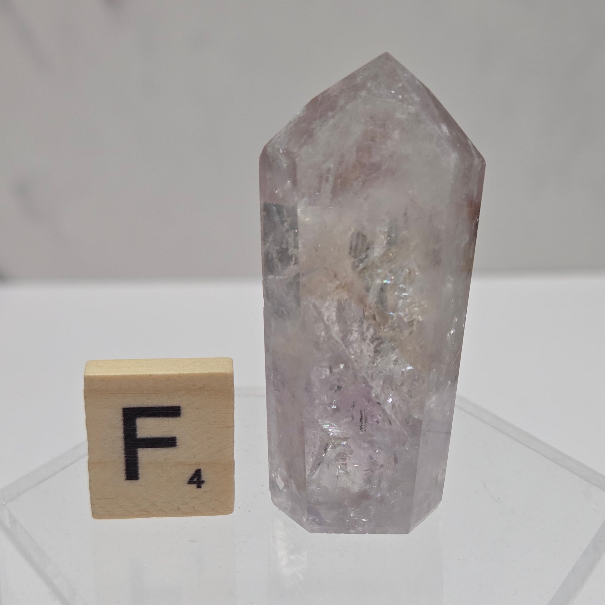 Crystal with a letter 'F' on a wooden block against a white geometric patterned background