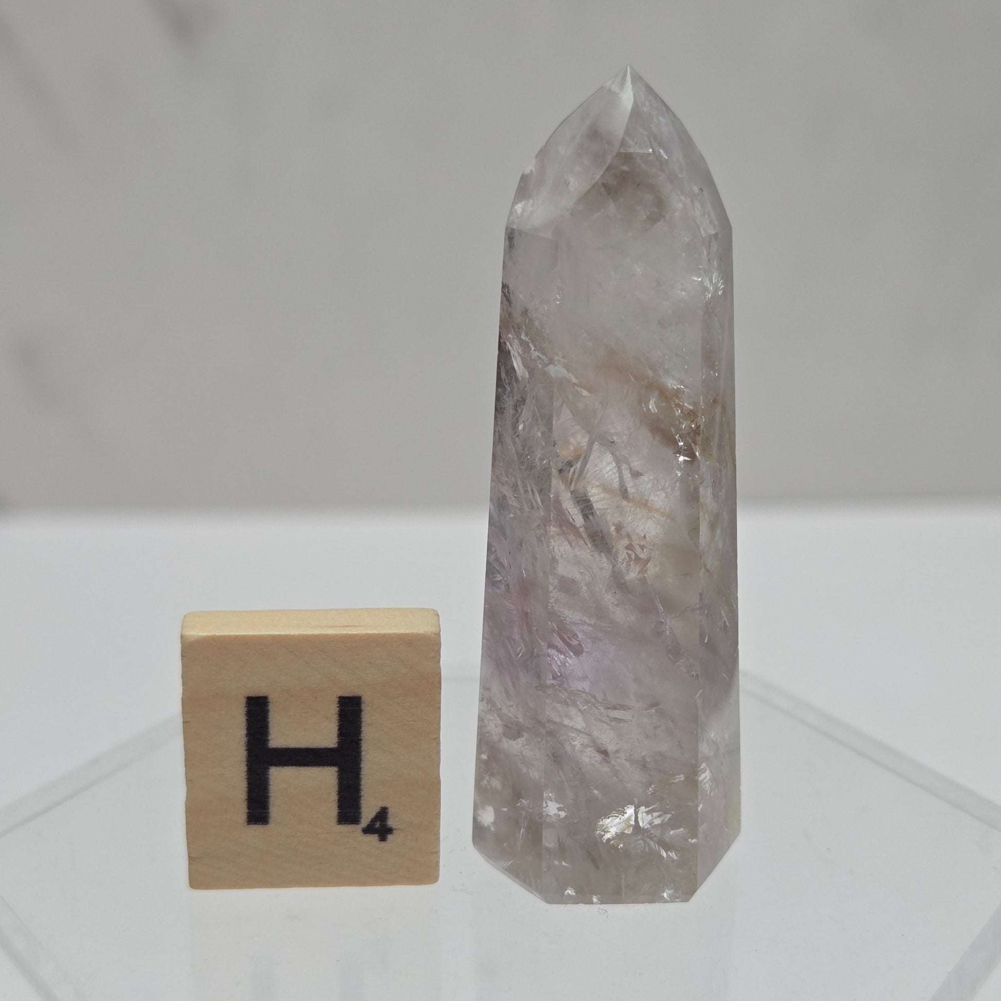 Crystal point and wooden block with letter 'H' on a white background