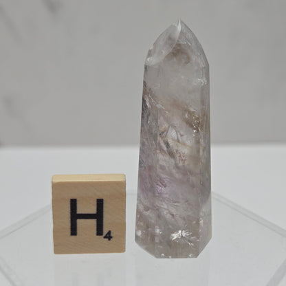 Crystal point and wooden block with letter 'H' on a white background