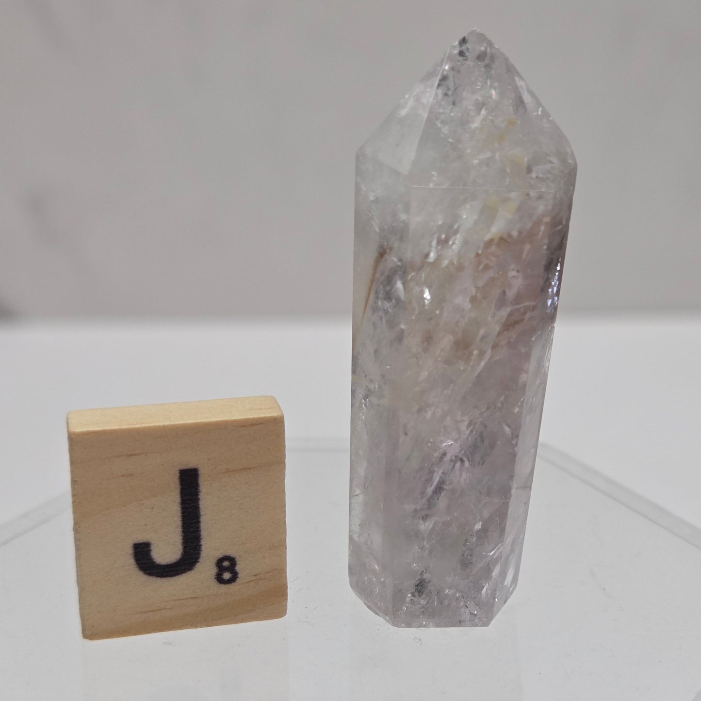 Clear crystal rock on a white background with a wooden block featuring the letter 'U'.