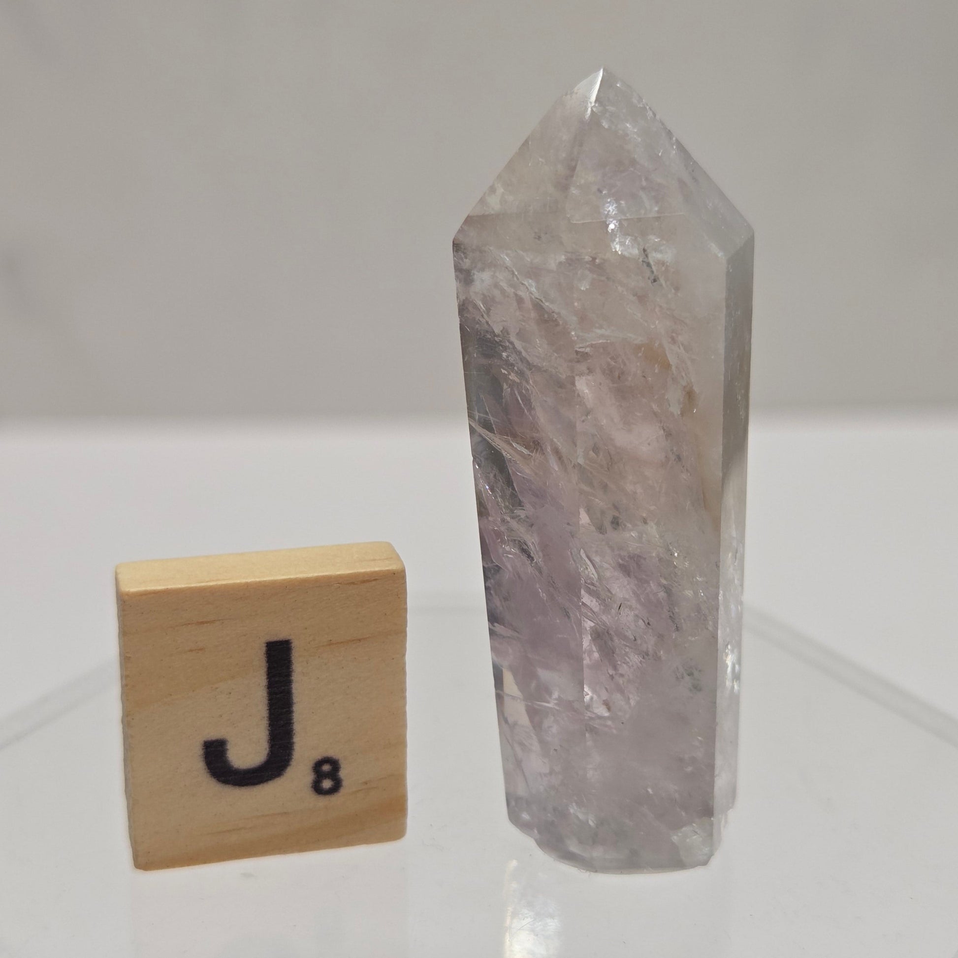 Crystal on a white tiled wall with a wooden block featuring a letter 'U'.