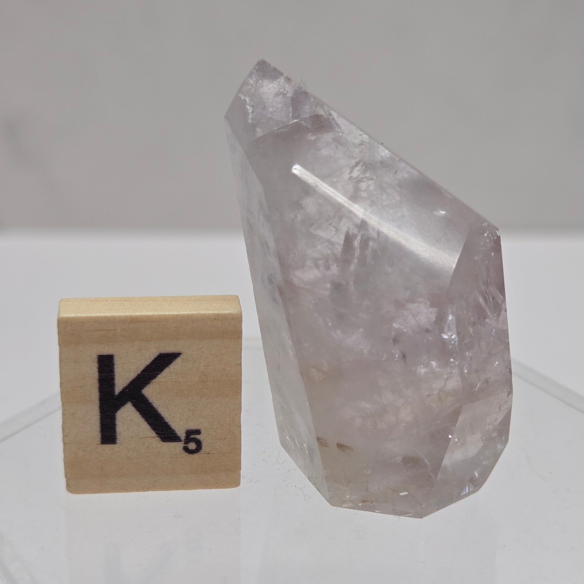Crystal on a wooden block with 'K' symbol against a white tiled wall