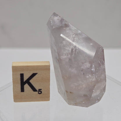 Crystal on a wooden block with 'K' symbol against a white tiled wall