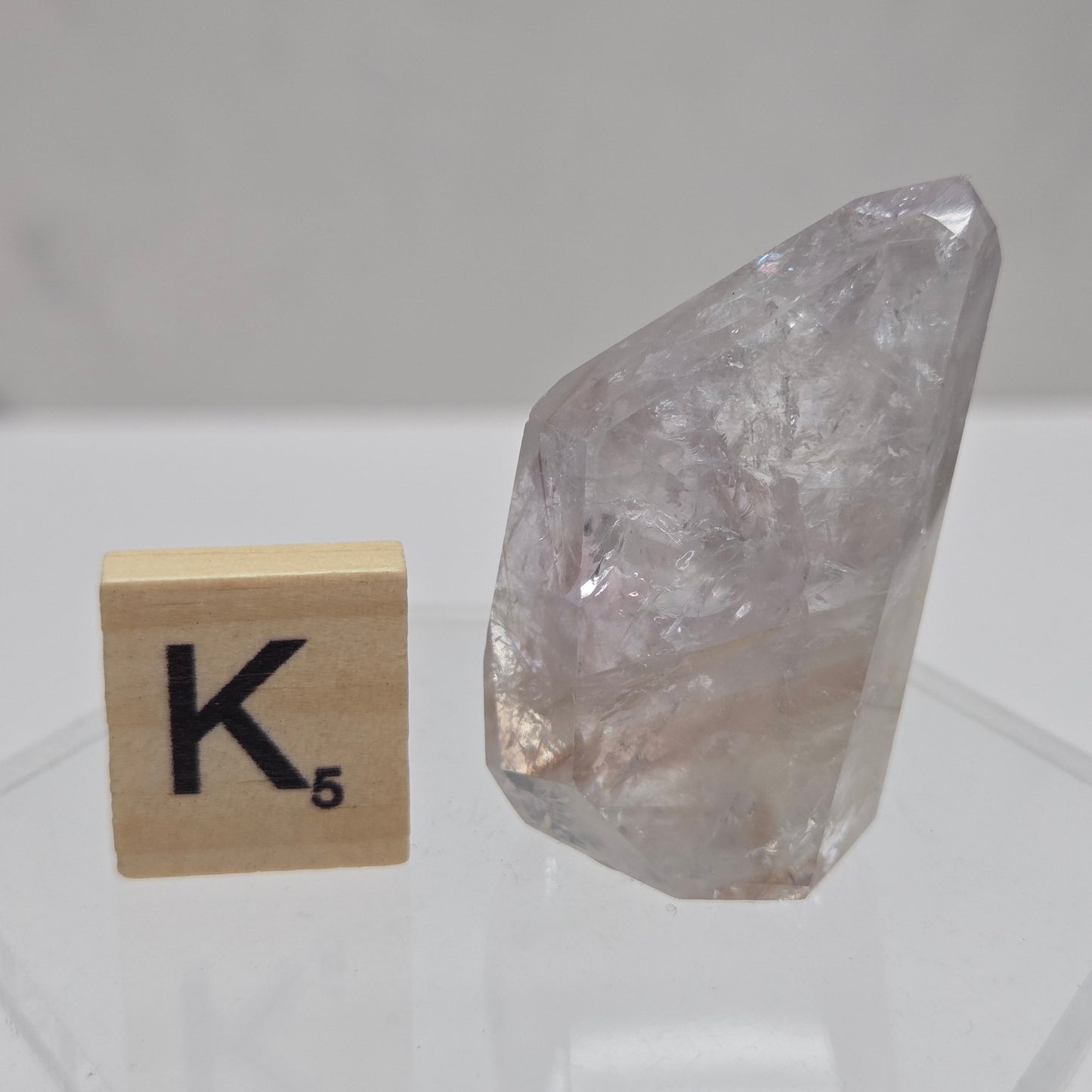 Crystal-like object on a white tiled wall with a wooden block featuring a symbol.