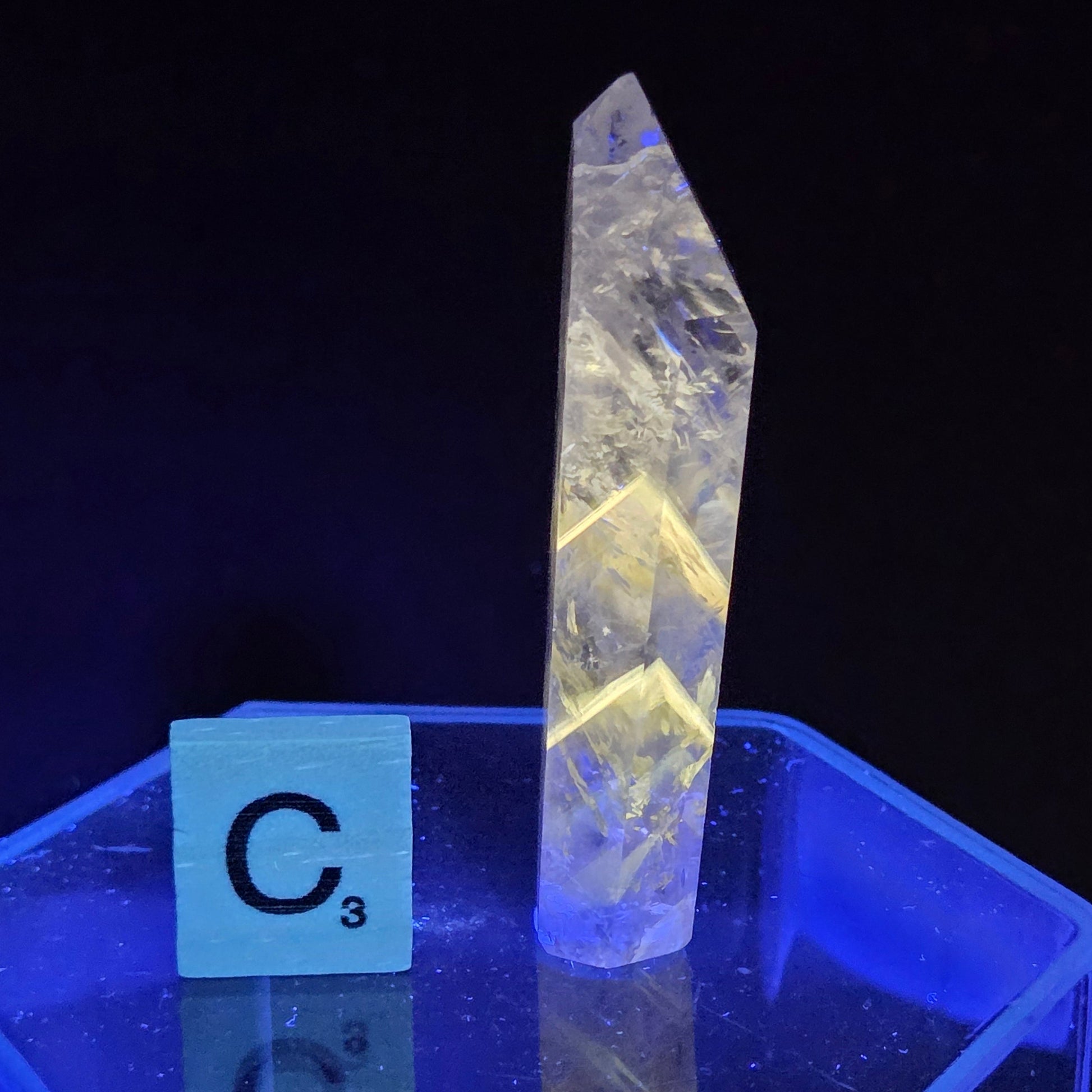 Crystal-like object under a blue light with a label on a dark background