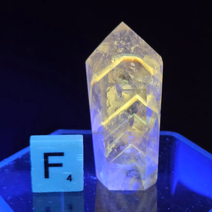 Crystal-like object under a blue light with a label 'F' on a reflective surface.