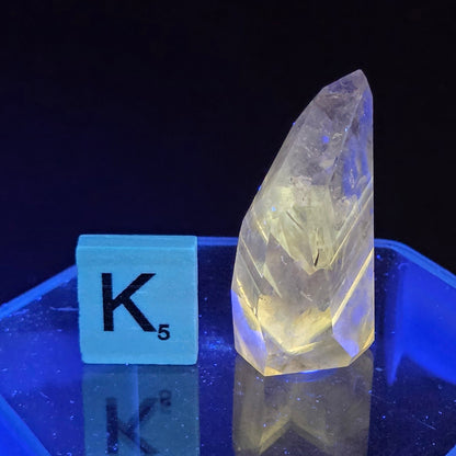 Clear crystal or gemstone under a blue light with measurement labels.
