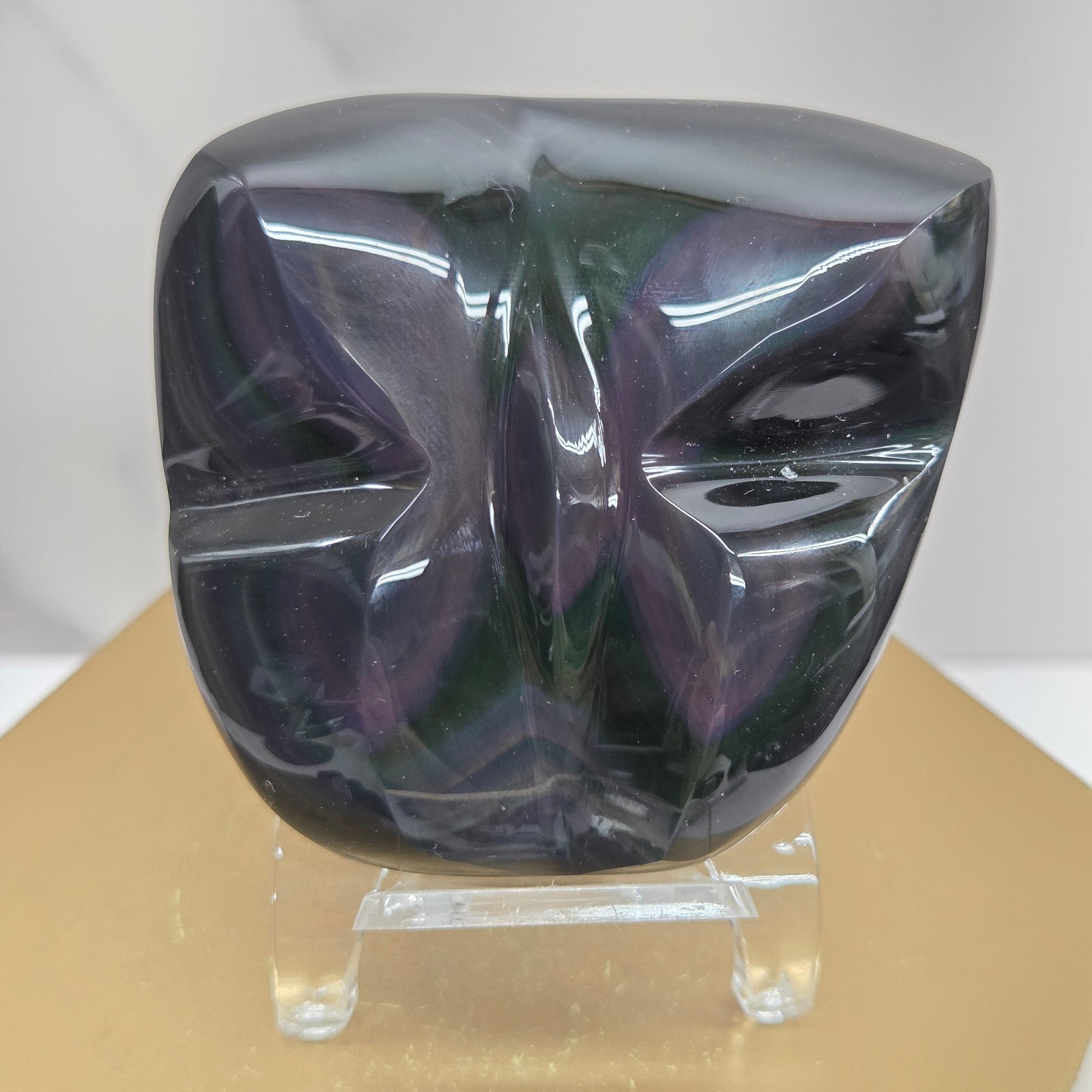Obsidian carving on an acrylic stand against a neutral background