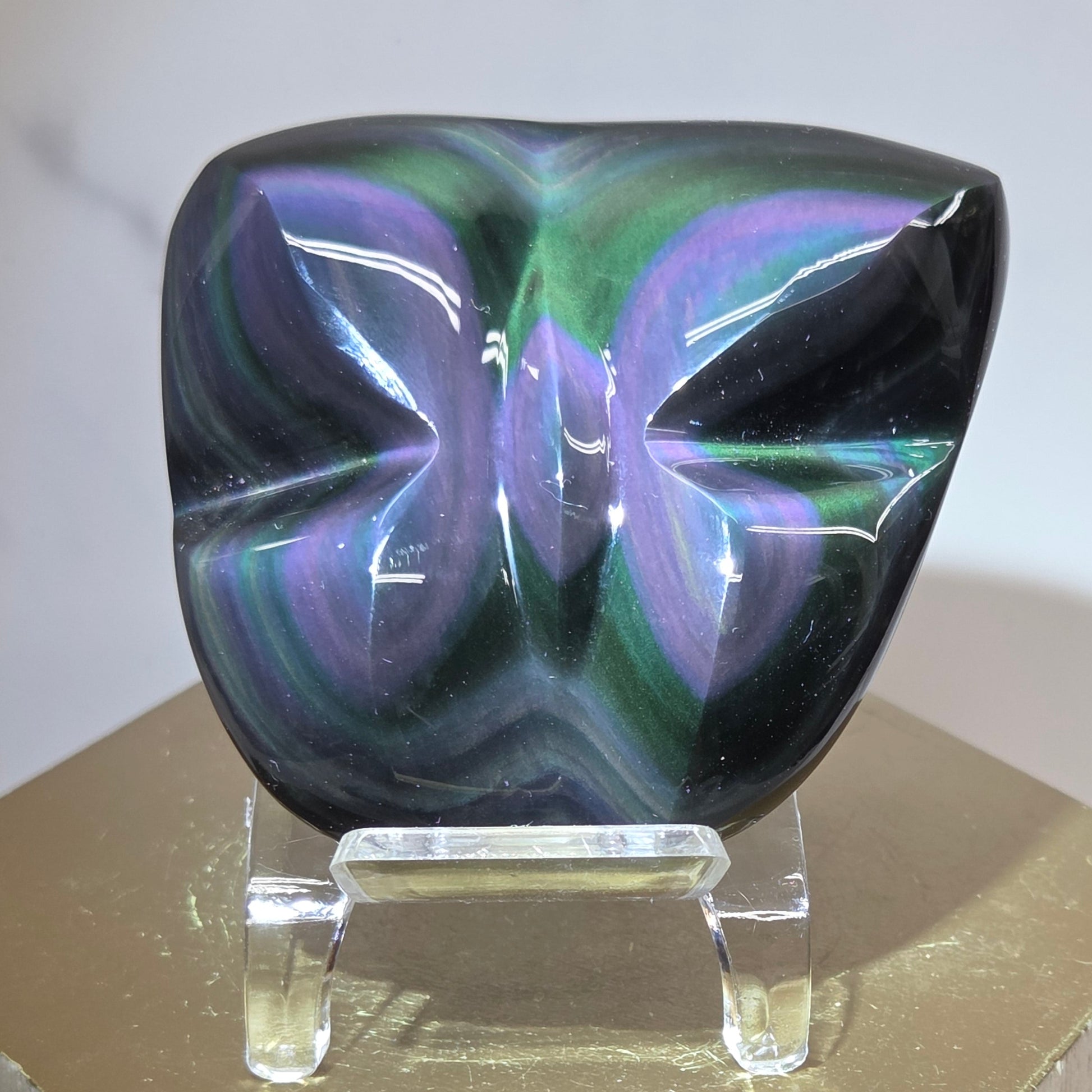 Obsidian carving on an acrylic stand against a neutral background