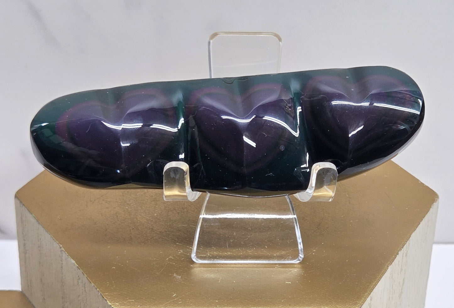Obsidian carving on an acrylic stand against a neutral background