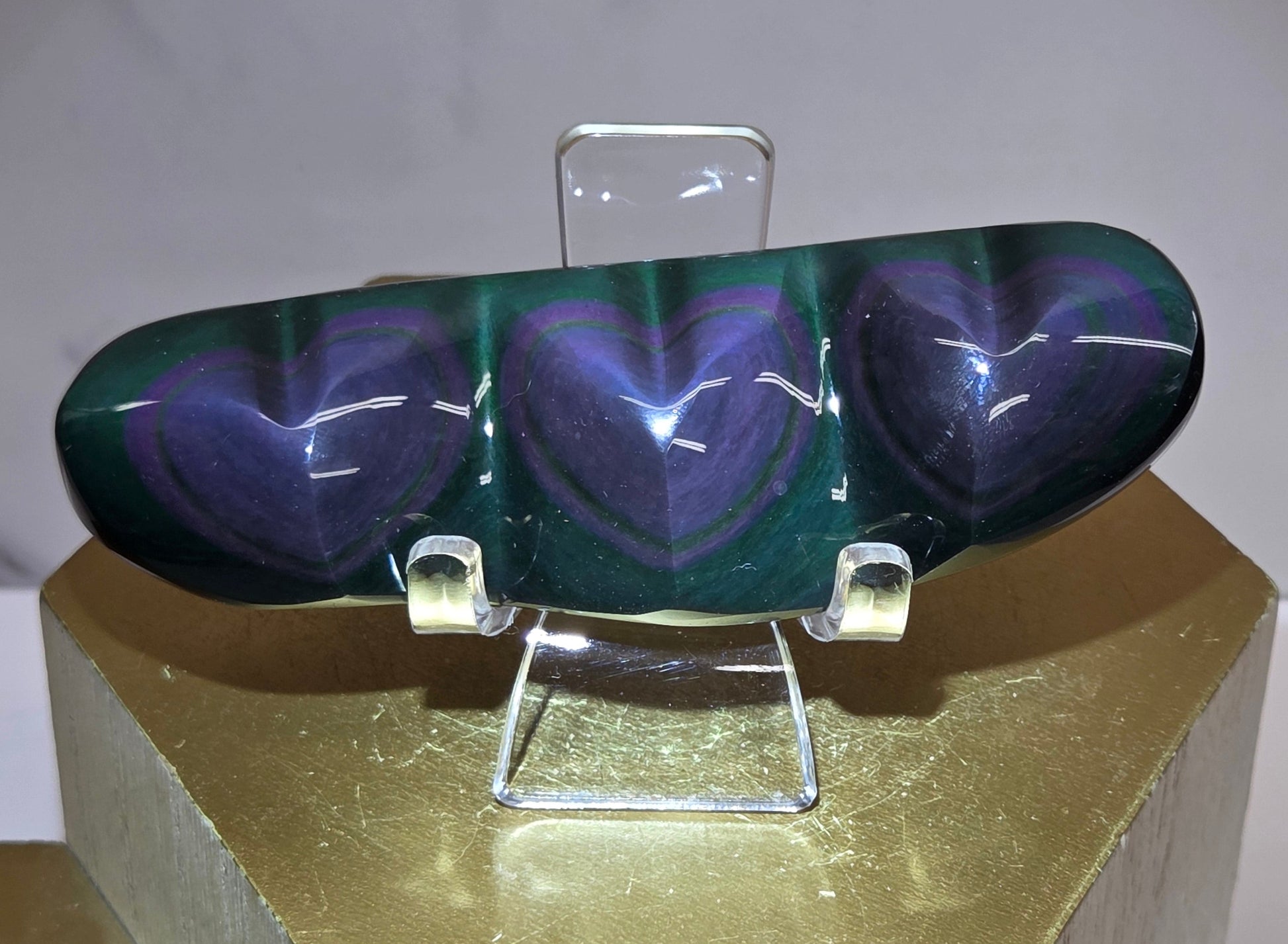 Obsidian carving on an acrylic stand against a neutral background