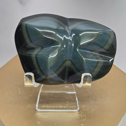 Obsidian carving on an acrylic stand against a neutral background
