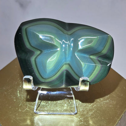 Obsidian carving on an acrylic stand against a neutral background