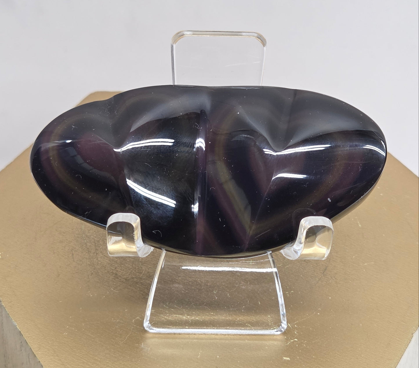 Obsidian carving on an acrylic stand against a neutral background
