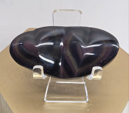 Obsidian carving on an acrylic stand against a neutral background