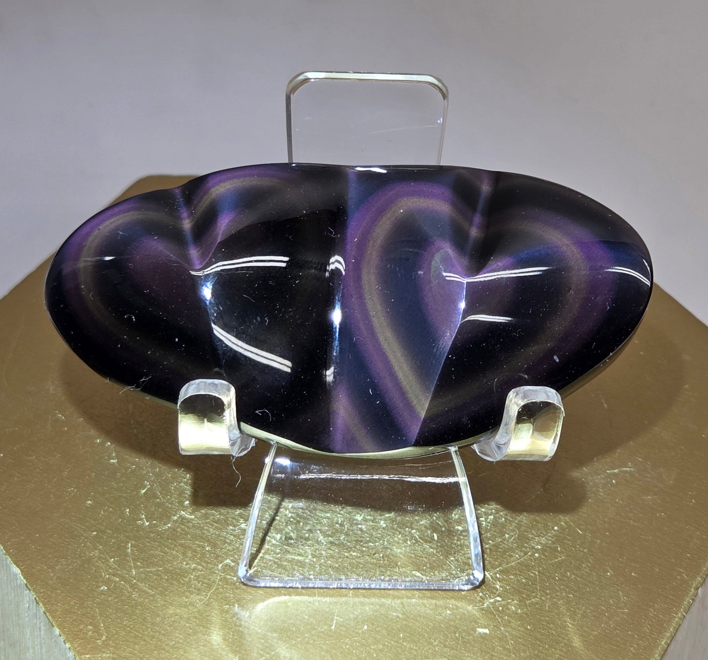 Obsidian carving on an acrylic stand against a neutral background