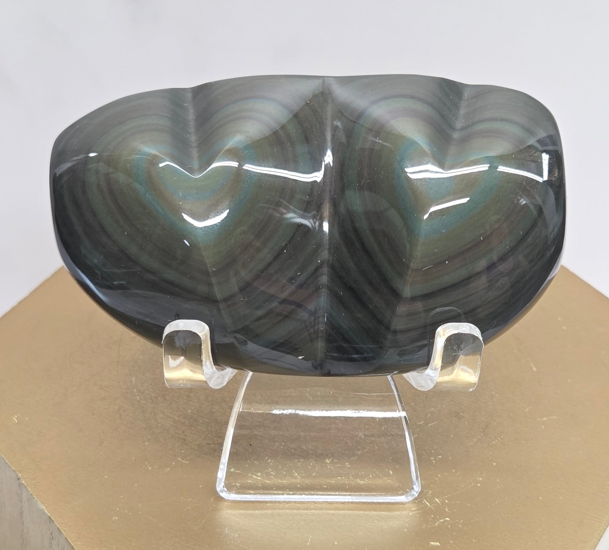 Obsidian carving on an acrylic stand against a neutral background